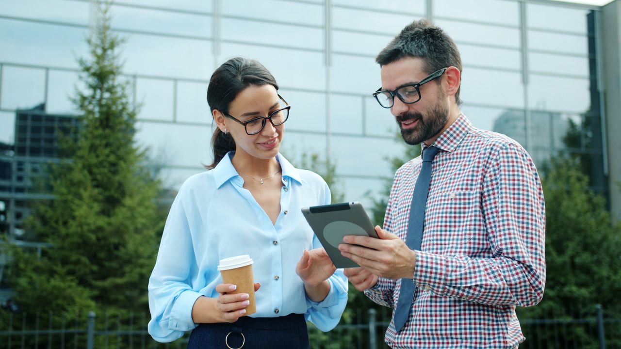 about-us Two professionals discussing work on a tablet outdoors.
