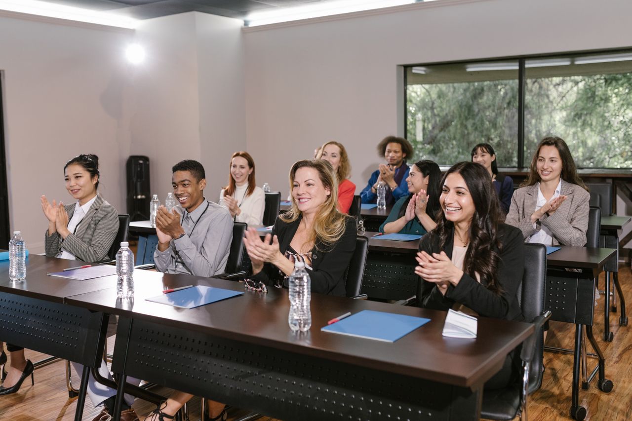 Crafting Captivating Headlines: Your awesome post title goes here A diverse group of adults applauding in a business seminar setting.